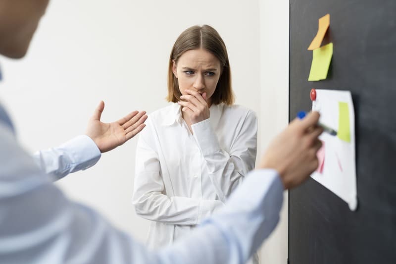 femme harcelée au travail, ennuyée devant un tableau rempli de post-it
